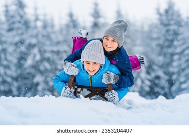 Happy family, children sledding in winter. Winter active sports fun outdoors. Wonderful winter landscape background.