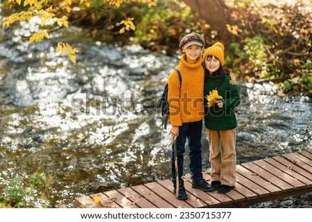 Happy family children walking on wooden bridge in autumn park.