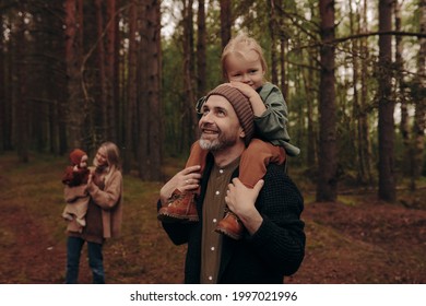 Happy Family With Children Walking In The Park.
Man Giving Young Girl Piggyback Ride Outdoors