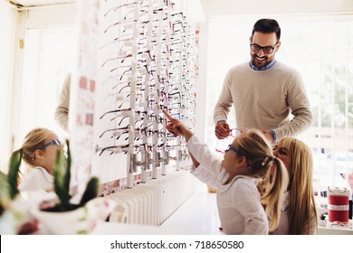 Happy Family Choosing Glasses In Optics Store. 