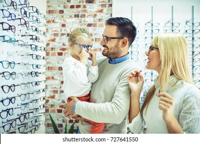 Happy Family Choosing Glasses In Optics Store. 