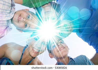 A Happy Family In A Circular Huddle Formation With A Bright Lens Flare In The Center With Copy Space For Your Text Or Image.