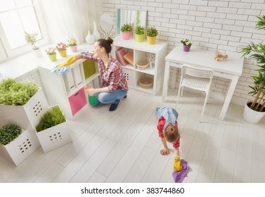 Happy Family Cleans The Room. Mother And Daughter Do The Cleaning In The House. A Young Woman And A Little Child Girl Dusting.