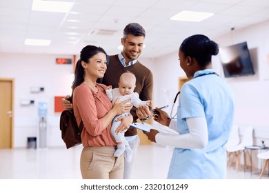 Happy family communicating with African American pediatric nurse in waiting room of a medical clinic. - Powered by Shutterstock