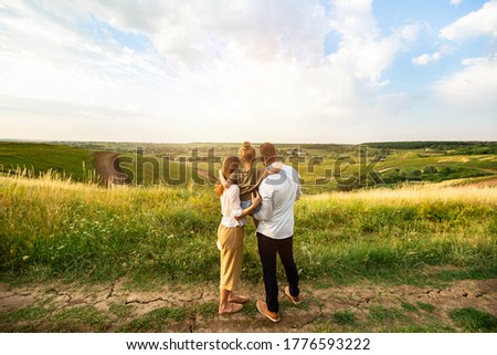 Happy Family Concept. Back view of mother, father and daughter looking and enjoying landscape on sunset