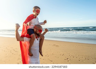 Happy family concept. Father and son playing superhero on the beautiful sunset beach , having fun together outdoors, wearing red masks and capes. Summer vacation. Copy space.
 - Powered by Shutterstock