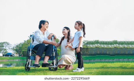 Happy family concept. Senior female patient sitting in wheelchair with mother and Daughter Relaxing in front of house outdoors - Powered by Shutterstock