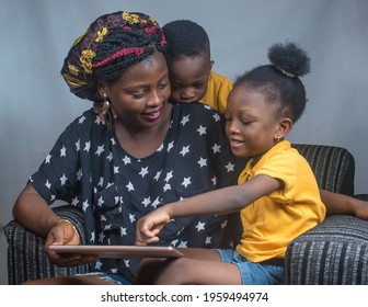 
Happy family consisting of a mother and her boy and girl children sitting happily together and playing with a big smart phone or phone tab on a sofa chair with phone in their hands 
