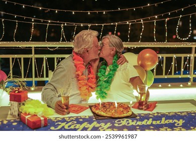 Happy family couple kissing celebrating birthday at night party on home terrace - Two elderly people having fun together - Holidays lifestyle concept - Powered by Shutterstock