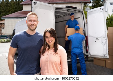 Happy Family Couple And Movers Unload Boxes From Truck