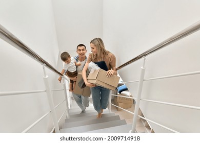 Happy Family Couple New Home Owners Real Estate Buyers Or Renters With Toddler Kid Child Son Carrying Boxes Going Up Stairs On Moving Day Arriving Into New Apartment. Relocation, Mortgage, Removals.