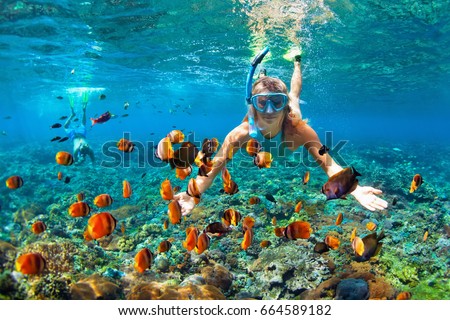 Happy family - couple in snorkeling masks dive deep underwater with tropical fishes in coral reef sea pool. Travel lifestyle, outdoor water sport adventure, swimming lessons on summer beach vacation