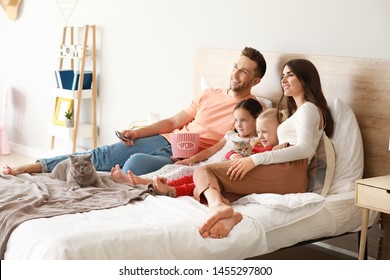 Happy family with cute cats watching TV on bed at home - Powered by Shutterstock