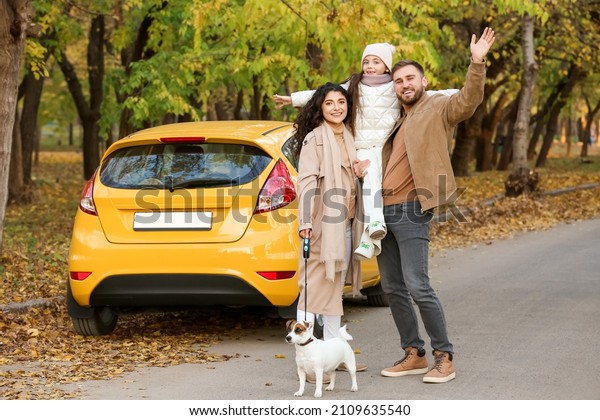 Happy family with cute dog near yellow car in park on\
autumn day