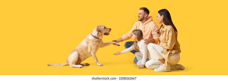 Happy family and cute Labrador dog on yellow background - Powered by Shutterstock