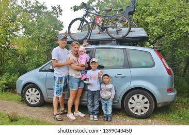 Happy Family: Dad, Mom, Two Sons And Small Daughter On Background Of Ford Focus C-max Car With Thule Trunk And Bicycles On Roof Before Trip. Five 5 People. Tver, Russia 2012. Sunny Summer Day 