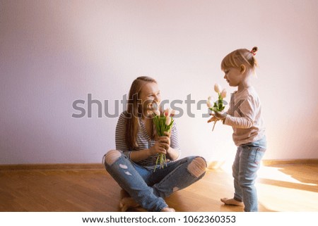 Happy family. Daughter gives a bouquet of flowers (tulips) to her mother in the room. Naturally laughed. Mother's Day.