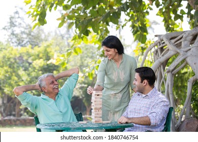 Happy Family And Daughter Playing The Wooden Blocks Tower At Par