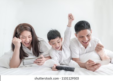 Happy family and digital technology. family parents and son lying on the bed using smart phones success winning. - Powered by Shutterstock