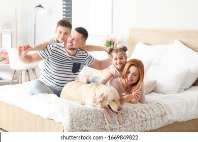 Happy Family With Dog In Bedroom At Home