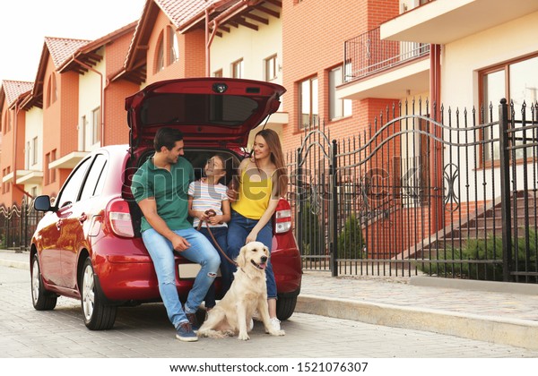 Happy family with dog\
near car on street