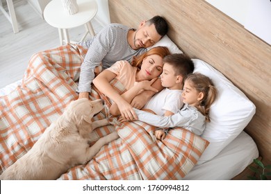 Happy Family With Dog Sleeping In Bed At Home