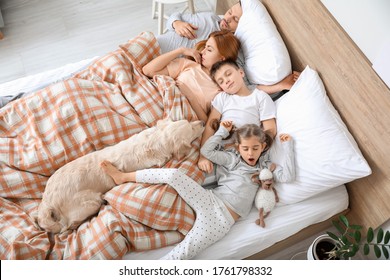 Happy family with dog sleeping in bed at home