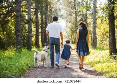 Happy Family With Dog Walking In The Park