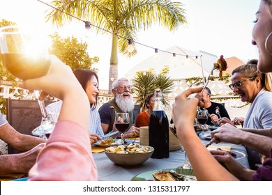 Happy Family Doing A Dinner During Sunset Time Outdoor - Group Of Diverse Friends Having Fun Dining Together Outside - Concept Of Lifestyle People, Food And Weekend Activities 