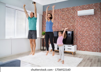 Happy Family Doing Jumping Fitness Exercise At Home