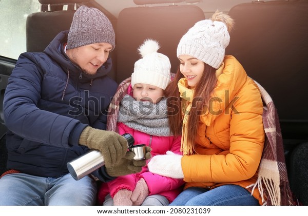 Happy\
family drinking hot tea in park on winter\
day
