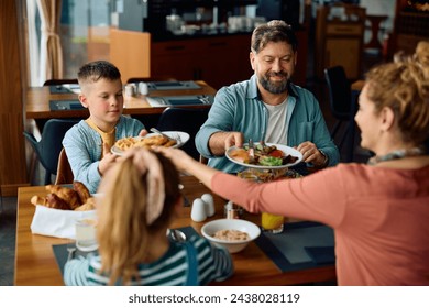 Happy family eating breakfast at dining table in hotel restaurant.  - Powered by Shutterstock