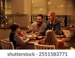 Happy family eating at dining table on Christmas Eve.