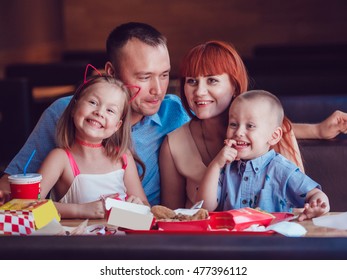 Happy Family Eating Fast Food In Restaurant All Together