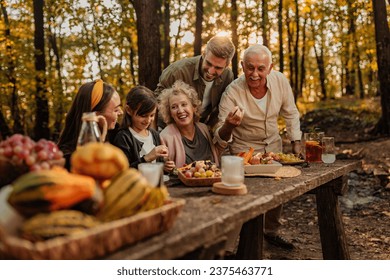 Happy family eating fruit, croissants and drinking ice tea while having a picnic in the woods - Powered by Shutterstock