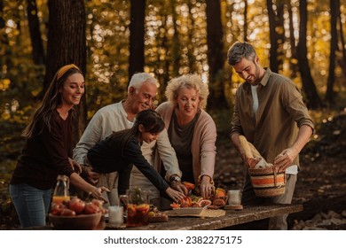 Happy family is eating fruits, croissants and baguettes while having a picnic in the woods during fall - Powered by Shutterstock