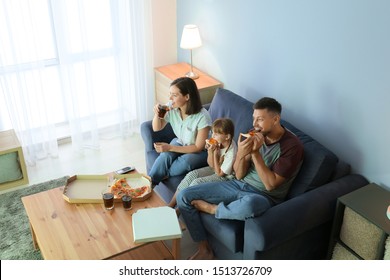 Happy Family Eating Pizza While Watching TV At Home