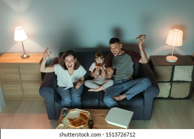 Happy Family Eating Pizza While Watching TV At Home