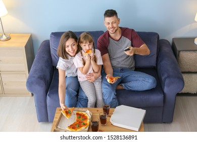 Happy Family Eating Pizza While Watching TV At Home