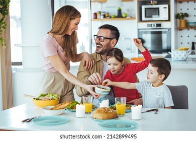 Happy family eating together in the kitchen. Dad and boy take tomatoes. Everyone is happy and satisfied. Home recreation and food preparation on weekends. The concept of community and enjoyment - Powered by Shutterstock