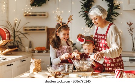 Happy family elderly grandmother and two little kids make Christmas homemade cookies together, standing behind table in kitchen decorated for xmas, children cooking with grandma during winter holidays - Powered by Shutterstock