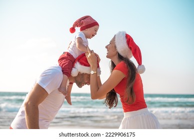 happy family enjoy on beach in vacation, holiday in new year and Christmas. son on shoulder of father, fun and happiness near sea together. white and red clothes and Santa hats. - Powered by Shutterstock