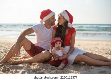 happy family enjoy on beach in vacation, holiday in new year and Christmas. sit on sand get fun near sea together. white and red clothes and Santa hats. - Powered by Shutterstock