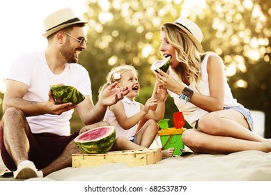 Happy Family Is Enjoying Beach And Eating Watermelon.