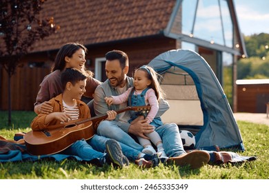 Happy family enjoying in camping day while boy is playing acoustic guitar.  - Powered by Shutterstock