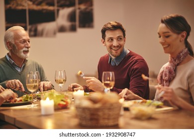 Happy family enjoying in conversation during a meal at dining table. Focus is on young man. 