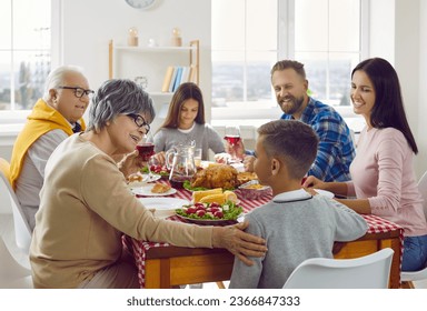 Happy family enjoying cozy dinner on weekend or holiday. Multigenerational family having festive Thanksgiving meal at home. Mom, dad, grandpa, grandma and children sitting at table and eating together - Powered by Shutterstock