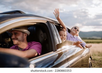 Feliz familia disfrutando de manejar en su nuevo auto eléctrico.