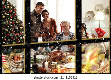 Happy Family Enjoying Festive Dinner Indoors, View Through Window. Christmas Celebration