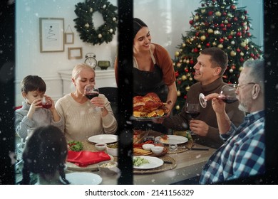 Happy Family Enjoying Festive Dinner At Home, View Through Window. Christmas Celebration